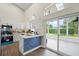 Modern kitchen with white cabinets, sleek appliances, and a blue paneled island seamlessly connects to a bright sunroom at 1161 Roxboro Rd, Longwood, FL 32750