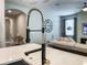 Close-up of a kitchen faucet and countertop with living room in background at 12795 Bosworth Ave, Windermere, FL 34786