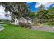 Charming white cottage-style home with mature trees, lush lawn, and a waterfront view at 1504 E Gore St, Orlando, FL 32806