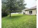 A spacious, grassy backyard with a mature shade tree provides privacy and serenity at 1574 Derby Glen Dr, Orlando, FL 32837
