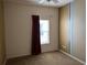 A simple bedroom with carpet floors, neutral walls, and a window with dark red curtains at 1574 Derby Glen Dr, Orlando, FL 32837