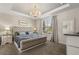 Elegant primary bedroom features a tray ceiling, chandelier lighting and a plush king-size bed at 1592 Carey Palm Cir, Kissimmee, FL 34747