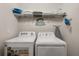 Efficient laundry room features modern washer and dryer, with built-in shelving for organized storage at 1592 Carey Palm Cir, Kissimmee, FL 34747