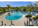 Beautiful community pool surrounded by palm trees, lounge chairs, and tables on a sunny day at 1592 Carey Palm Cir, Kissimmee, FL 34747