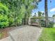 Backyard features a gravel courtyard with a charming wooden swing and mature greenery, offering a serene retreat at 1640 Mayfield Ave, Winter Park, FL 32789