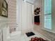 A neutral patterned bathroom featuring a toilet, shower with curtain, decorative wreath, patterned wall paper, and a window at 1640 Mayfield Ave, Winter Park, FL 32789