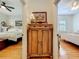 Hallway view with hardwood floors, wooden cabinet with artwork in the center, and a peek into bedrooms on either side at 1640 Mayfield Ave, Winter Park, FL 32789