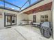 Covered patio area with stone floors, an outdoor dining table, grill, and a comfortable seating area for entertaining at 1640 Mayfield Ave, Winter Park, FL 32789