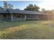 Expansive backyard with lush lawn, mature trees, and a single story home featuring a row of windows along the back at 17836 Palm St, Umatilla, FL 32784