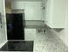 Functional kitchen featuring stainless steel sink, electric cooktop, granite countertops, and white cabinets at 17836 Palm St, Umatilla, FL 32784