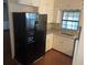 Well-lit kitchen featuring sleek, modern black fridge, white cabinets, and granite countertops at 17836 Palm St, Umatilla, FL 32784