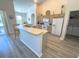 Open concept kitchen with an extended breakfast bar, white appliances, and easy access to the laundry room at 204 Birkdale St, Davenport, FL 33897