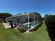 Aerial view of the screened-in pool and patio area surrounded by lush landscaping and a well-manicured lawn at 204 Birkdale St, Davenport, FL 33897