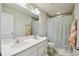 Bright bathroom featuring a double vanity, large mirror, and tiled shower with a decorative curtain at 2056 Airedale Way, Lake Alfred, FL 33850