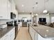 Spacious kitchen featuring white cabinets, granite countertops, and stainless steel appliances, open to the living area at 2056 Airedale Way, Lake Alfred, FL 33850
