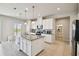 Well-lit kitchen with white cabinetry, a granite island, stainless steel appliances, and tile flooring at 2056 Airedale Way, Lake Alfred, FL 33850