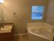 Bathroom featuring a garden tub, single sink vanity, and a window for natural light at 2131 Kaylas Ct, Orlando, FL 32817