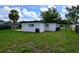 A view of the backyard, featuring a large lawn area, recently painted home, and side gate at 226 Palmyra Dr, Orlando, FL 32807