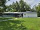 View of the home's manicured lawn with screened-in pool and white brick facade at 2417 Yale Ave, Sanford, FL 32771