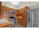 Well-equipped kitchen featuring stainless steel appliances, wood cabinets, tile backsplash, and sleek flooring at 3016 Rogan Rd, Orlando, FL 32812