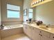Bathroom featuring a large tub and a double sink vanity at 3539 Maple Ridge Loop, Kissimmee, FL 34741