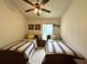 Shared bedroom with twin beds, a ceiling fan, and a nightstand with a lamp at 3539 Maple Ridge Loop, Kissimmee, FL 34741