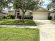 Single-Gathering home with red entry door, large two-car garage, and lush landscaping at 3539 Maple Ridge Loop, Kissimmee, FL 34741