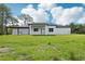 Expansive backyard featuring a pergola with an outdoor kitchen, manicured lawn, and lush surrounding trees at 42157 Tamarac St, Eustis, FL 32736