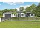 Contemporary home featuring a dark gray garage door and a well-manicured front yard with a wooden fence at 42157 Tamarac St, Eustis, FL 32736