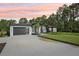 Modern home with a spacious driveway and manicured lawn, set against a backdrop of lush trees at sunset at 42157 Tamarac St, Eustis, FL 32736