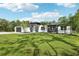 Beautiful modern home with lush green lawn, palm trees, and a striking dark and white color scheme at 42157 Tamarac St, Eustis, FL 32736