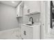 Modern laundry room with white cabinets, quartz countertop, black hardware, and a stainless steel faucet at 42157 Tamarac St, Eustis, FL 32736