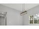 Modern rectangular pendant light with decorative glass elements against a gray wall and window at 42157 Tamarac St, Eustis, FL 32736