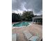Community pool surrounded by lounge chairs and a covered seating area on a cloudy day at 454 Wilton Cir, Sanford, FL 32773