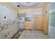 Outdated kitchen with damaged walls, missing cabinets and dated tile floors in need of complete renovation at 535 Romano Ave, Orlando, FL 32807