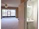 View of the airy living room with ceiling fan, leading to the outdoor balcony and featuring an adjacent half bathroom at 650 Shropshire Loop, Sanford, FL 32771