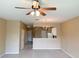 Open-concept living room with eat in kitchen, neutral color palette, and ceiling fan at 650 Shropshire Loop, Sanford, FL 32771