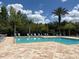 Swimming pool features lounge chairs on a brick patio, set against a background of mature tropical trees and a clear blue sky at 650 Shropshire Loop, Sanford, FL 32771