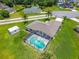 Aerial shot of the backyard featuring a screened pool, long driveway, lush grass and a storage shed surrounded by mature trees at 909 Hendon Place, Kissimmee, FL 34758