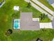 Overhead aerial shot of the house featuring a screened-in pool, grassy yard, tropical palms, and long driveway in sunny surroundings at 909 Hendon Place, Kissimmee, FL 34758