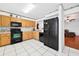 Bright kitchen with white tile floors, wooden cabinets, and a black appliance package at 909 Hendon Place, Kissimmee, FL 34758