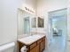 Well-lit bathroom featuring a spacious countertop, vanity with wood finish and a large mirror at 1008 Jackson St, The Villages, FL 32162