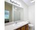 Well-lit bathroom featuring a spacious countertop, vanity with wood finish and a large mirror at 1008 Jackson St, The Villages, FL 32162