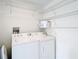 Efficient laundry room features a white washer and dryer, storage shelves, and neatly organized space at 1008 Jackson St, The Villages, FL 32162
