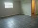 Neutral bedroom with tile flooring, a window, and access to an adjacent room at 1021 Golfside Ct, Kissimmee, FL 34741