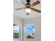 Bedroom featuring a ceiling fan and two windows with views of the sky and trees at 10580 Moss Rose Way, Orlando, FL 32832