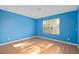 Cozy bedroom with bright blue walls, wood floors, and a window providing ample natural light at 1130 Burland Cir, Winter Garden, FL 34787