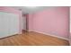 Bedroom features pink walls, wood laminate flooring, and closet with traditional doors at 1130 Burland Cir, Winter Garden, FL 34787