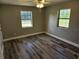 This bedroom includes wood-look flooring, neutral wall color and two windows at 13208 Massachusetts Ave, Astatula, FL 34705