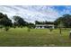 Sprawling front yard showcasing a cozy one-story home, mature trees, and a serene countryside atmosphere under a cloudy sky at 13208 Massachusetts Ave, Astatula, FL 34705